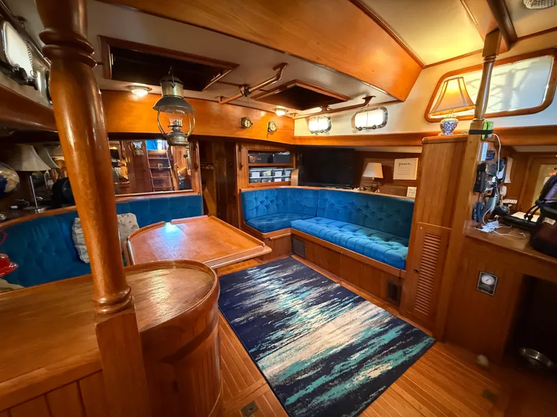 Cozy interior of 1986 Vagabond 47 yacht with wooden furnishings and blue seating.