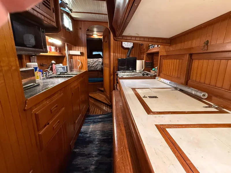 Interior of 1986 Vagabond 47 sailboat with wooden cabinetry and kitchen area.
