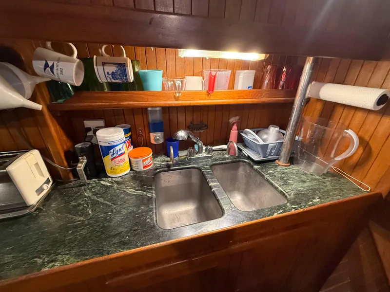 Galley kitchen in 1986 Vagabond 47 sailboat with double sink and wooden cabinetry.