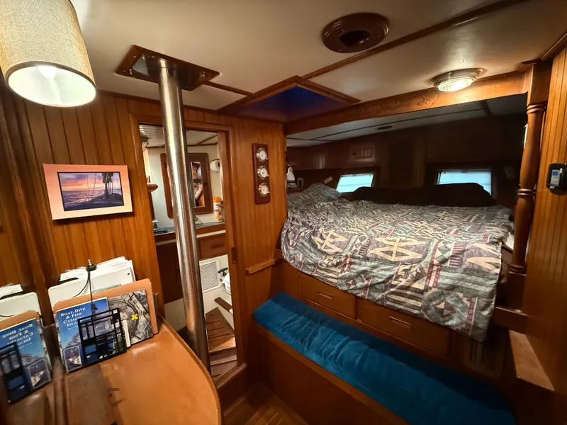 Cozy 1986 Vagabond 47 yacht interior with wooden paneling and a comfortable bed.