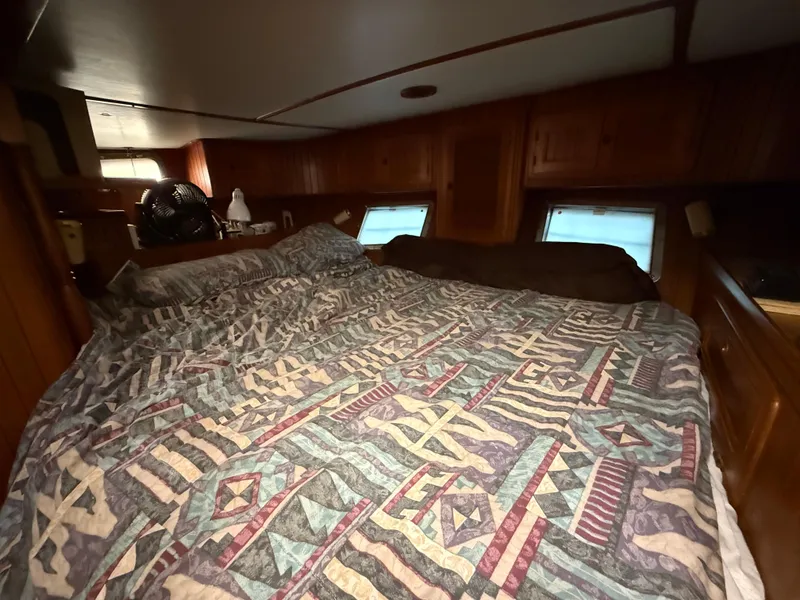 Cozy cabin interior of 1986 Vagabond 47 sailboat with patterned bedding and wooden accents.