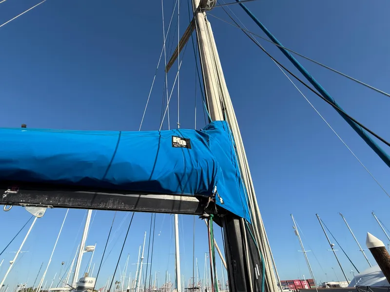 Sailboat mast and boom with blue cover, Vagabond 47, 1986, in marina under clear sky.