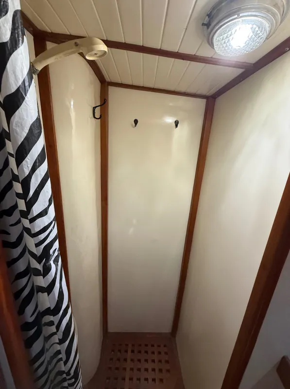 Compact shower area with zebra-patterned curtain in 1986 Vagabond 47 yacht.
