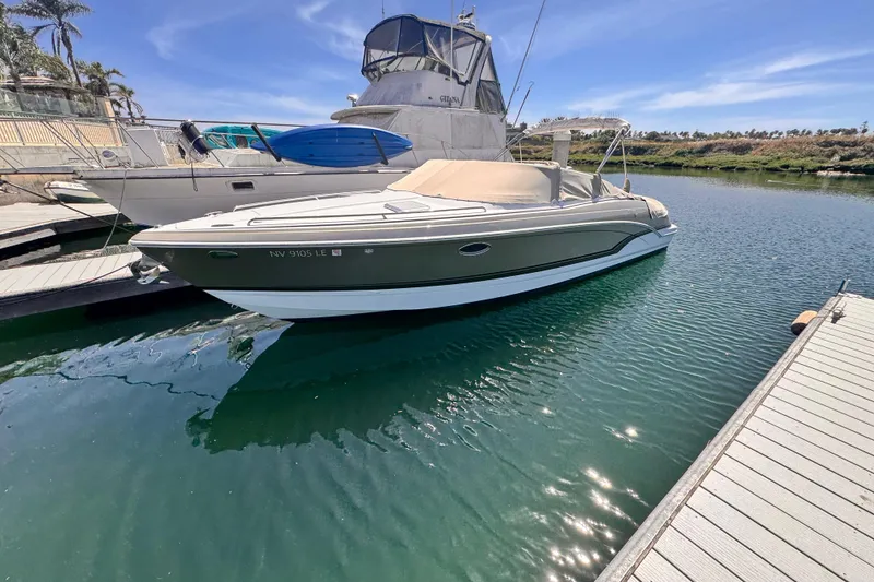 2012 Formula 290 Sun Sport boat docked in a serene marina under a clear blue sky.