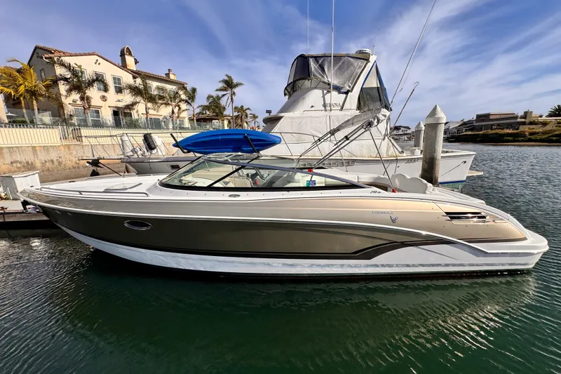 2012 Formula 290 Sun Sport boat docked in a marina with coastal homes in the background.