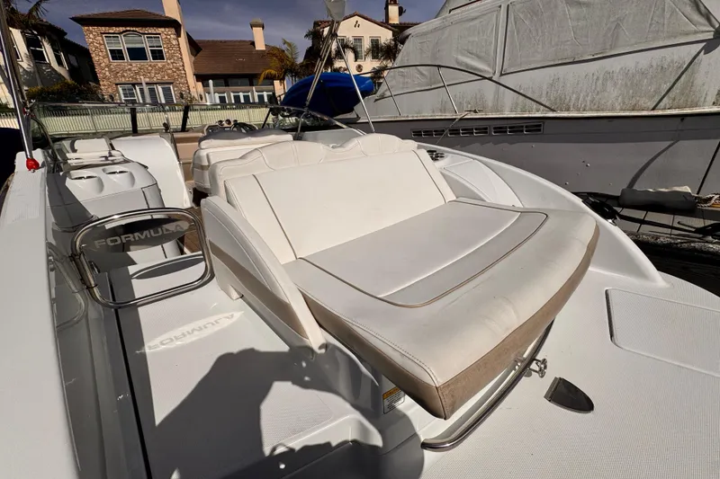 2012 Formula 290 Sun Sport boat with white seating, docked near waterfront homes.