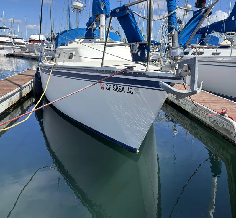 1985 Newport 30 sailboat docked in marina, reflecting on calm water.
