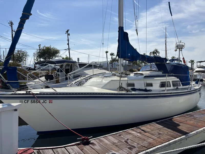 1985 Newport 30 sailboat docked at marina under clear blue sky.