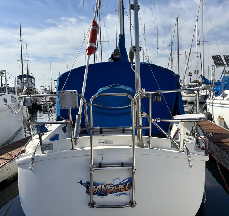 1985 Newport 30 sailboat docked at marina, featuring blue cover and stainless steel ladder.