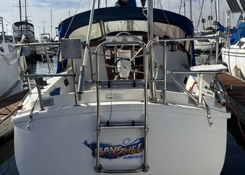 1985 Newport 30 sailboat docked in marina, rear view with stainless steel railings.