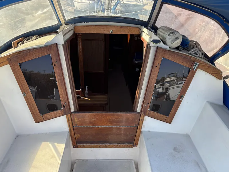 Cockpit view of a 1985 Newport 30 sailboat with open wooden cabin doors.