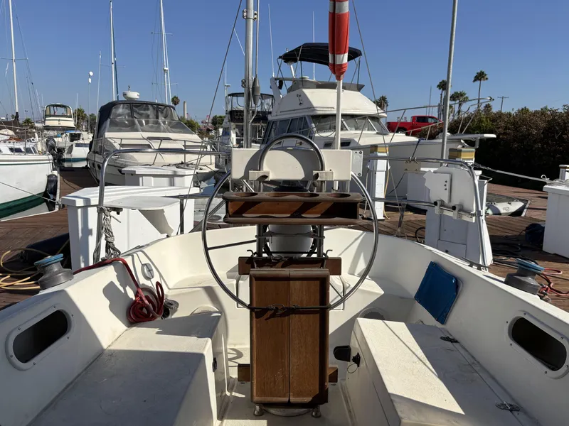 Cockpit view of a 1985 Newport 30 sailboat docked at a marina.