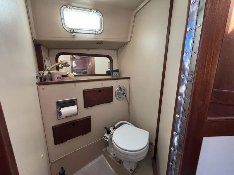 Compact bathroom in a 1985 Newport 30 sailboat with toilet and storage compartments.