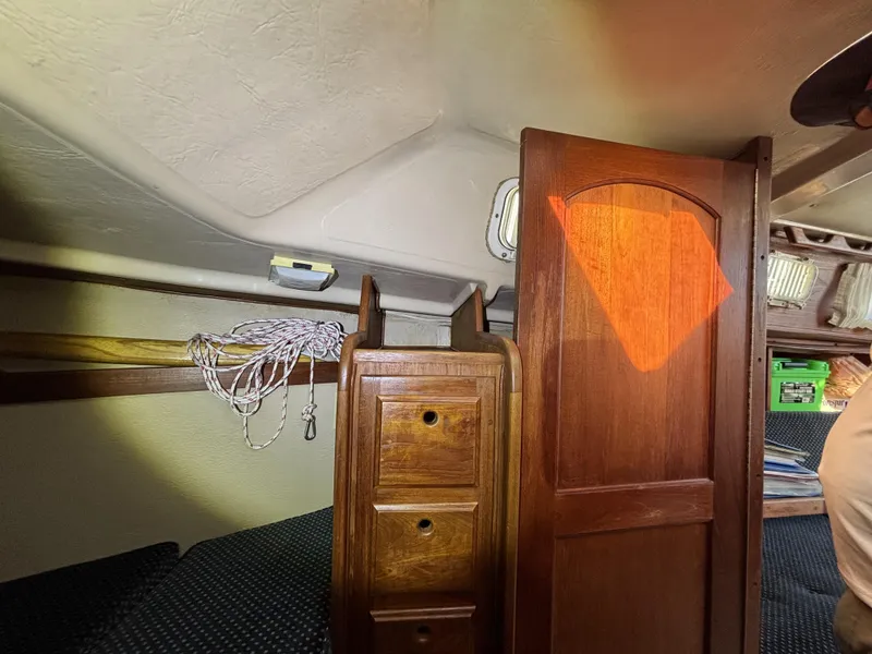 Interior of a 1985 Newport 30 sailboat with wooden cabinetry and seating area.
