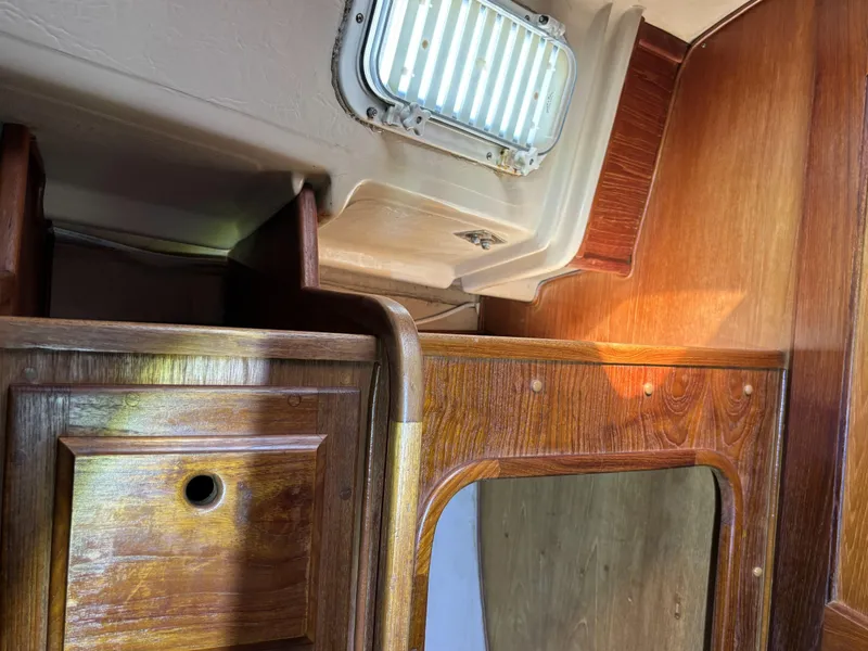 Interior of 1985 Newport 30 sailboat with wooden cabinetry and a small window.