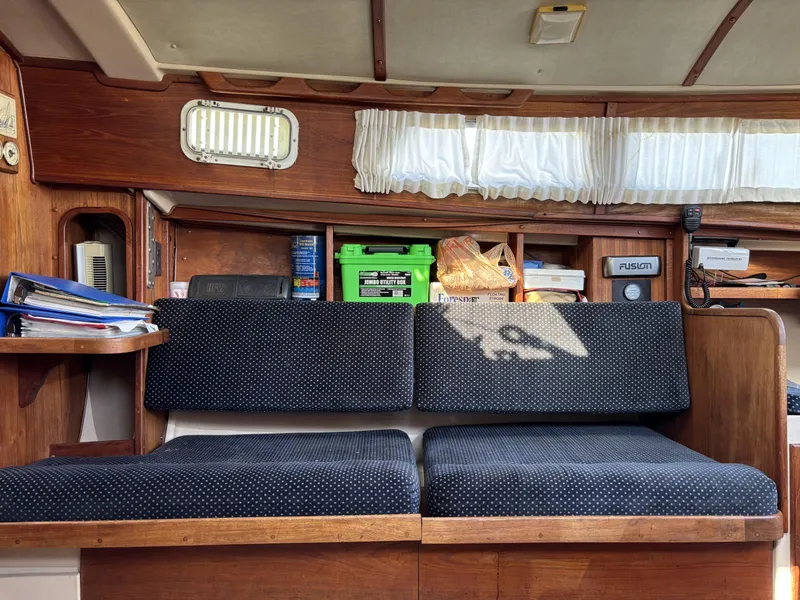 Interior of a 1985 Newport 30 sailboat with cushioned seating and storage shelves.