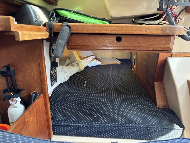 Cozy cabin interior of a 1985 Newport 30 sailboat with wooden accents and bedding.