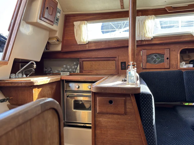 Interior of a 1985 Newport 30 sailboat, featuring a compact kitchen and cozy seating area.