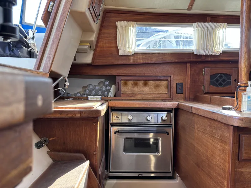 1985 Newport 30 yacht interior kitchen with wooden cabinetry and stainless steel oven.
