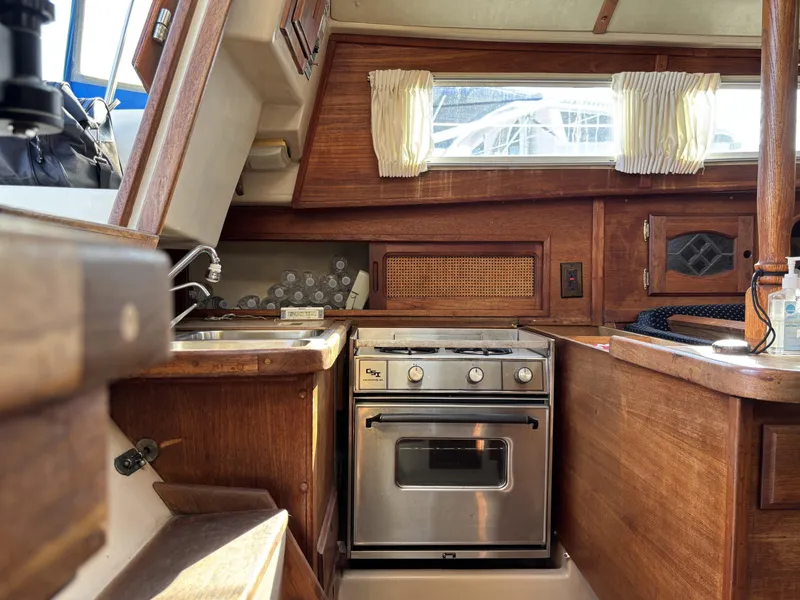 1985 Newport 30 yacht interior with wooden cabinetry and compact kitchen area.