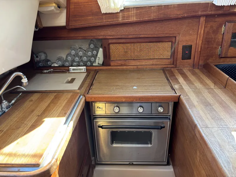 Wooden galley interior of 1985 Newport 30 sailboat with stove and sink.