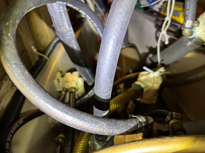 Tangled hoses and wires inside a 1985 Newport 30 boat engine compartment.