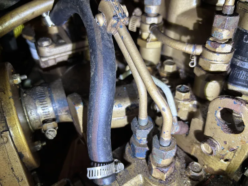 Close-up of 1985 Newport 30 engine components with hoses and metal fittings.