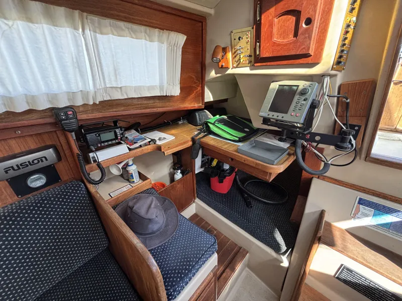 Interior of a 1985 Newport 30 sailboat with navigation equipment and wooden cabinetry.