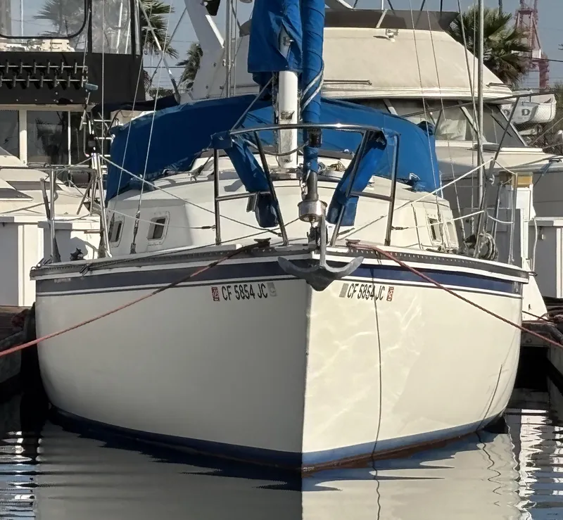 1985 Newport 30 sailboat docked in marina, featuring blue sail cover and white hull.
