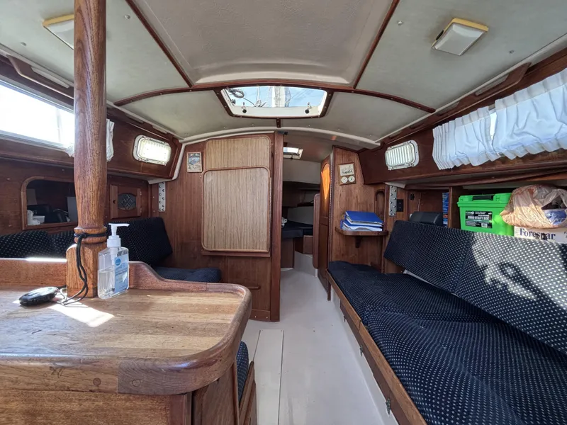 Interior of a 1985 Newport 30 sailboat with wooden furnishings and seating.