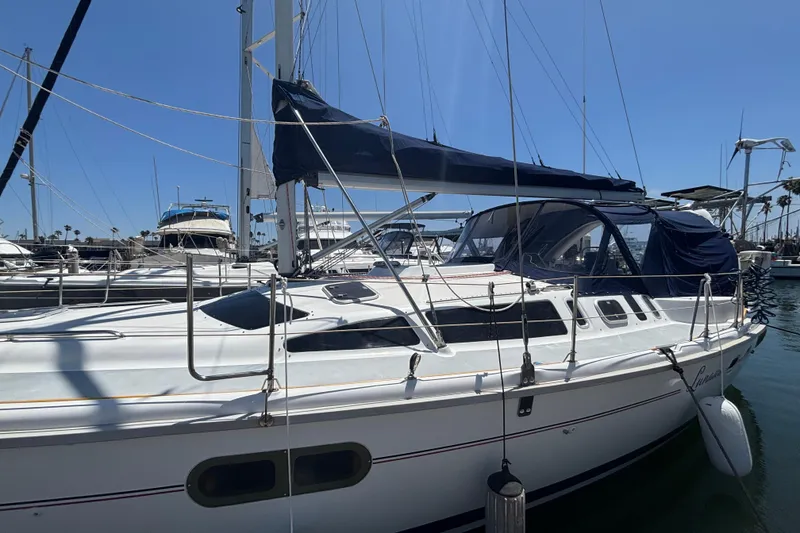 Sailboat docked in marina, 1999 Hunter 410 model, with blue canopy and clear skies.