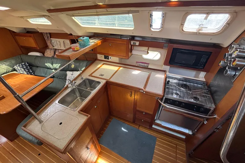 Interior of 1999 Hunter 410 yacht kitchen with wooden cabinetry and modern appliances.