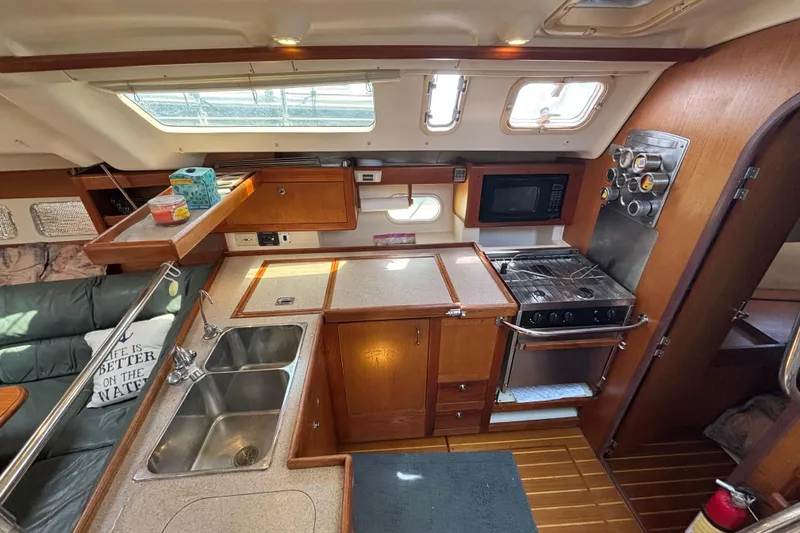 Interior of a 1999 Hunter 410 sailboat kitchen with stove, sink, and microwave.