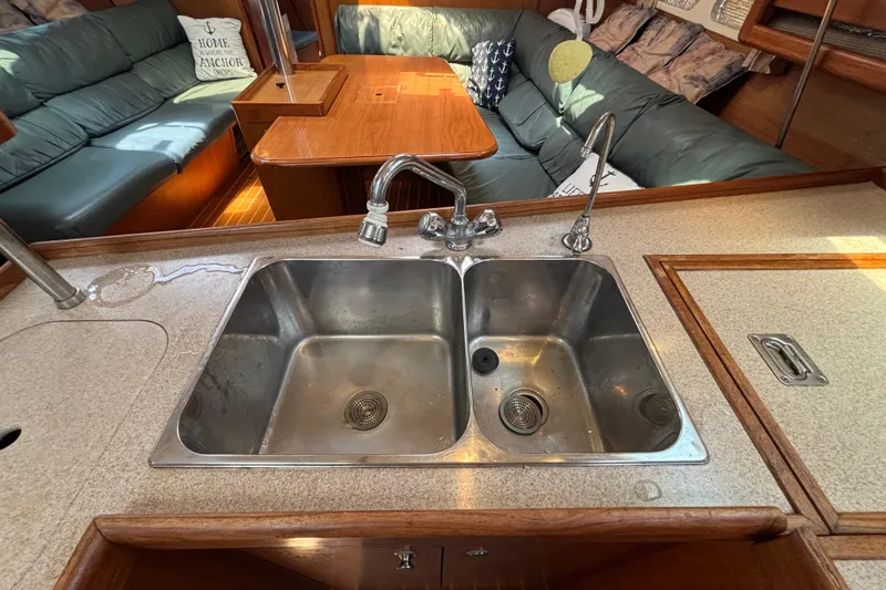 Interior of 1999 Hunter 410 yacht with dual sink and cozy seating area.