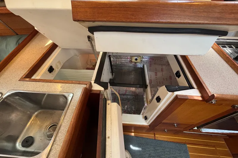 Interior of a 1999 Hunter 410 yacht kitchen with open storage compartments.