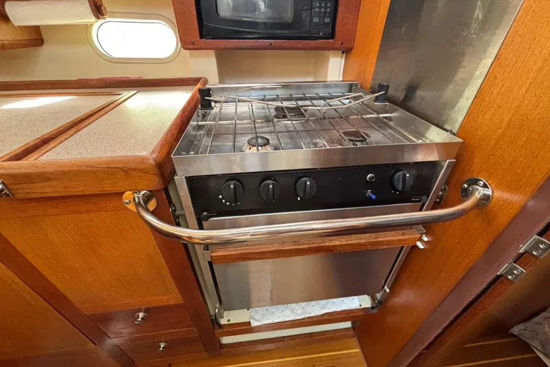 1999 Hunter 410 yacht kitchen with stove, oven, and microwave in wooden cabinetry.