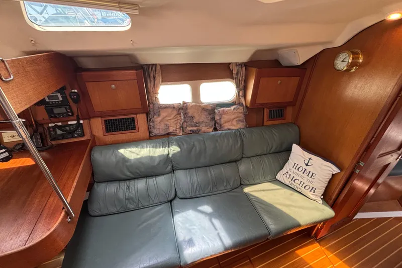 Cozy interior of 1999 Hunter 410 sailboat with green sofa and nautical decor.