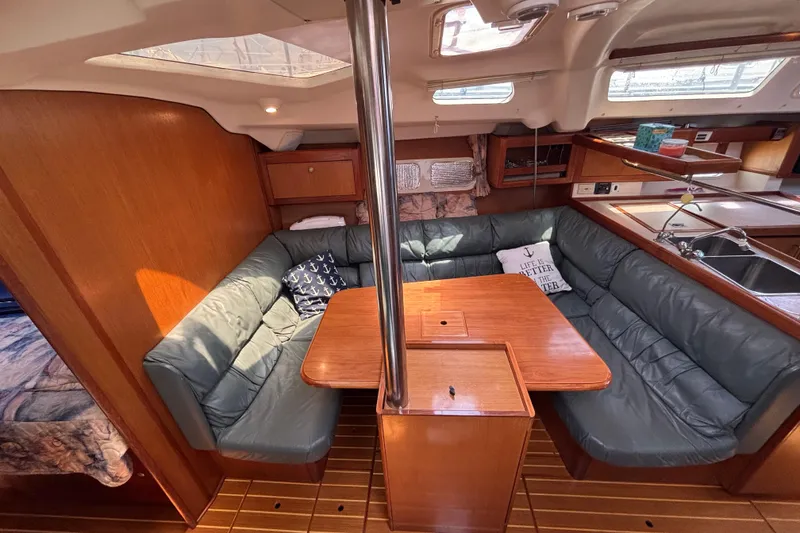 Cozy interior of 1999 Hunter 410 sailboat with cushioned seating and wooden table.