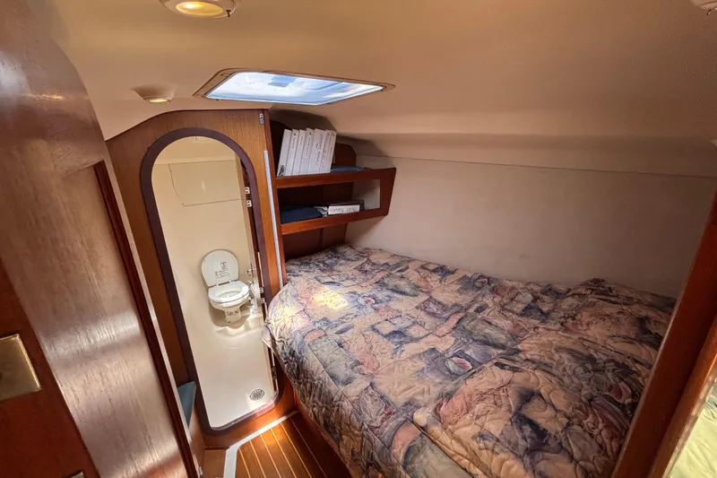 Cozy cabin interior of 1999 Hunter 410 sailboat with bed and compact bathroom.