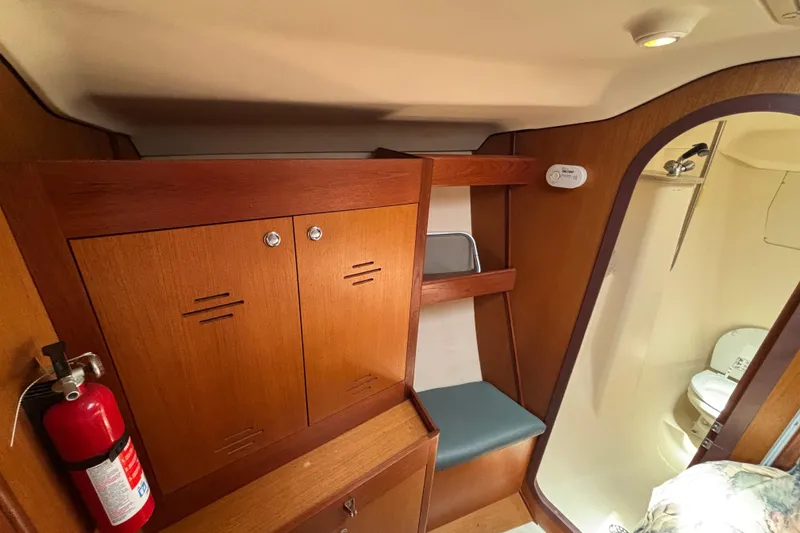 1999 Hunter 410 yacht interior with wooden cabinets, fire extinguisher, and compact bathroom.