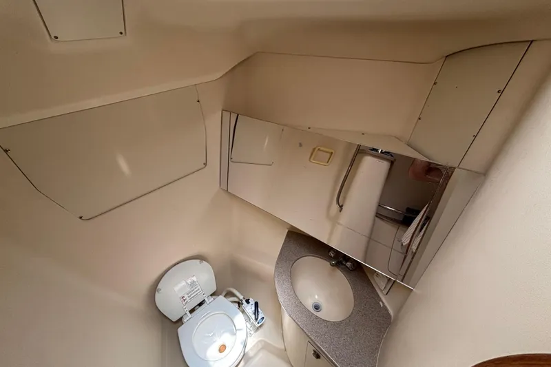 Compact bathroom in a 1999 Hunter 410 yacht, featuring a toilet, sink, and mirror.