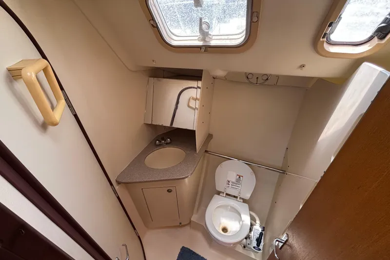 Compact bathroom in a 1999 Hunter 410 sailboat with toilet, sink, and storage.