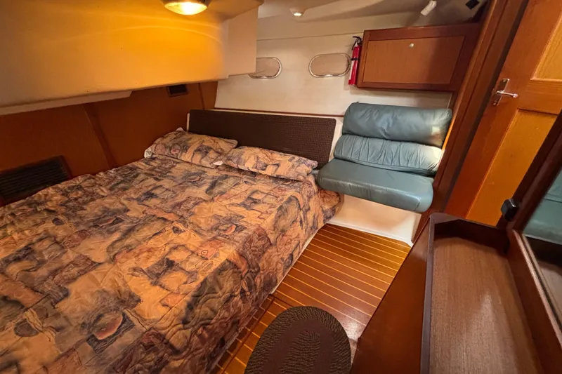 Cozy cabin interior of 1999 Hunter 410 sailboat with patterned bedding and wooden accents.