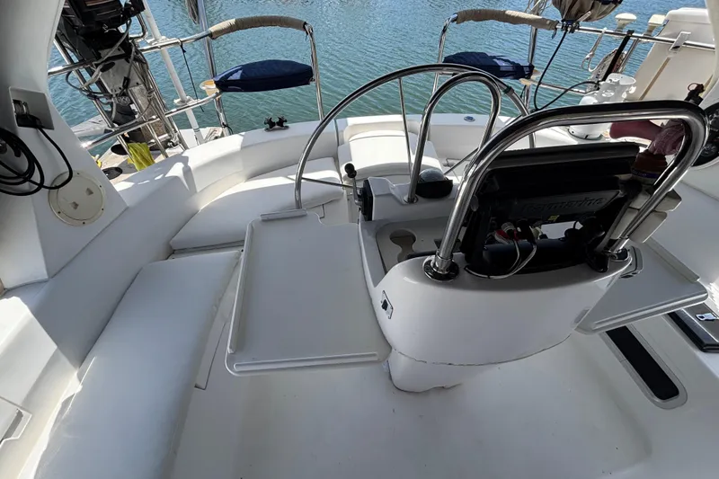 Cockpit of 1999 Hunter 410 sailboat with steering wheel and seating, overlooking water.