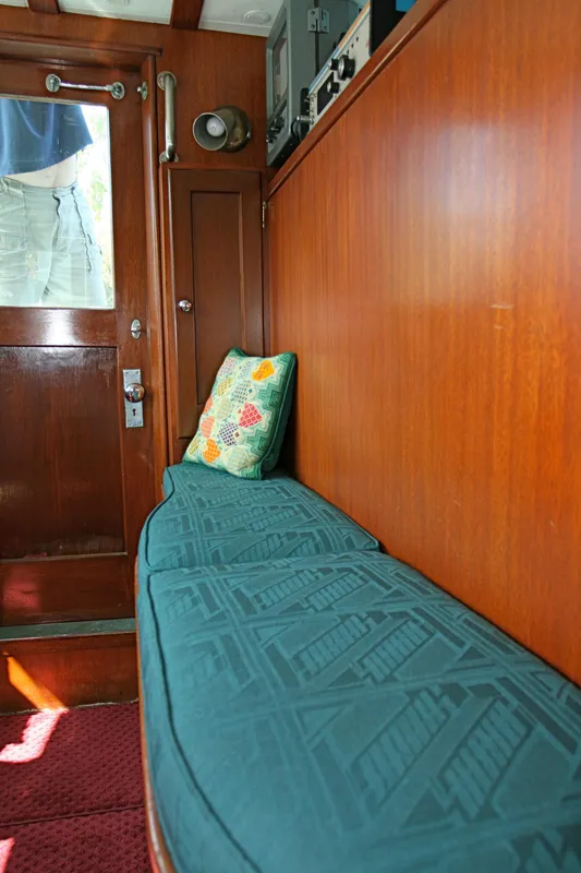 Interior of classic yacht with wooden walls and cushioned bench seating.