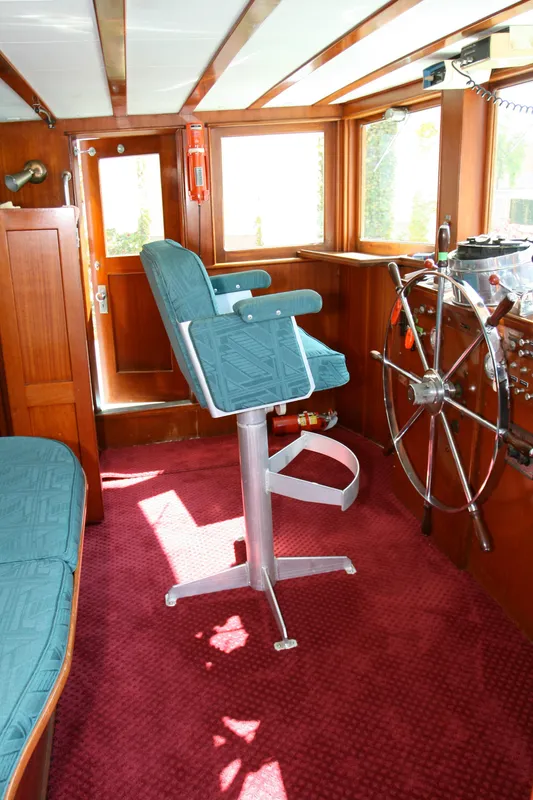 Interior of classic yacht with steering wheel and captain's chair, built in 1946.