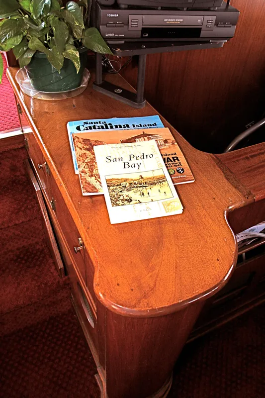 Wooden table with books and plant on a 1946 yacht.