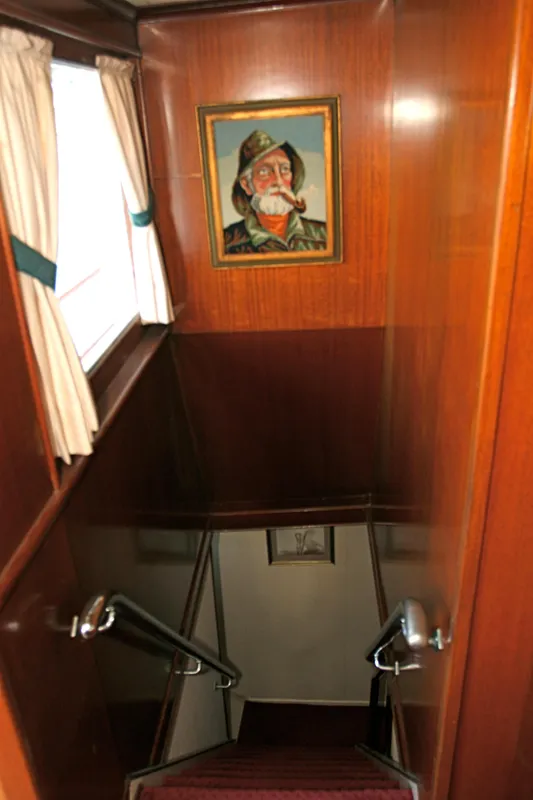 Wooden staircase in classic yacht with painting on the wall.