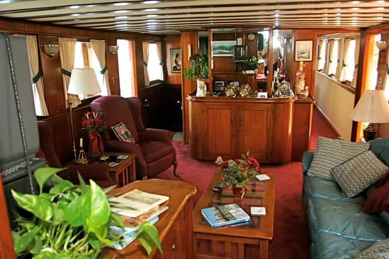 Interior of a classic yacht with wooden furnishings and plants, built in 1946.