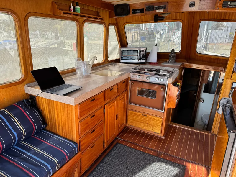 1979 Californian LRC Sedan Bridge interior with kitchen, laptop, and seating area.